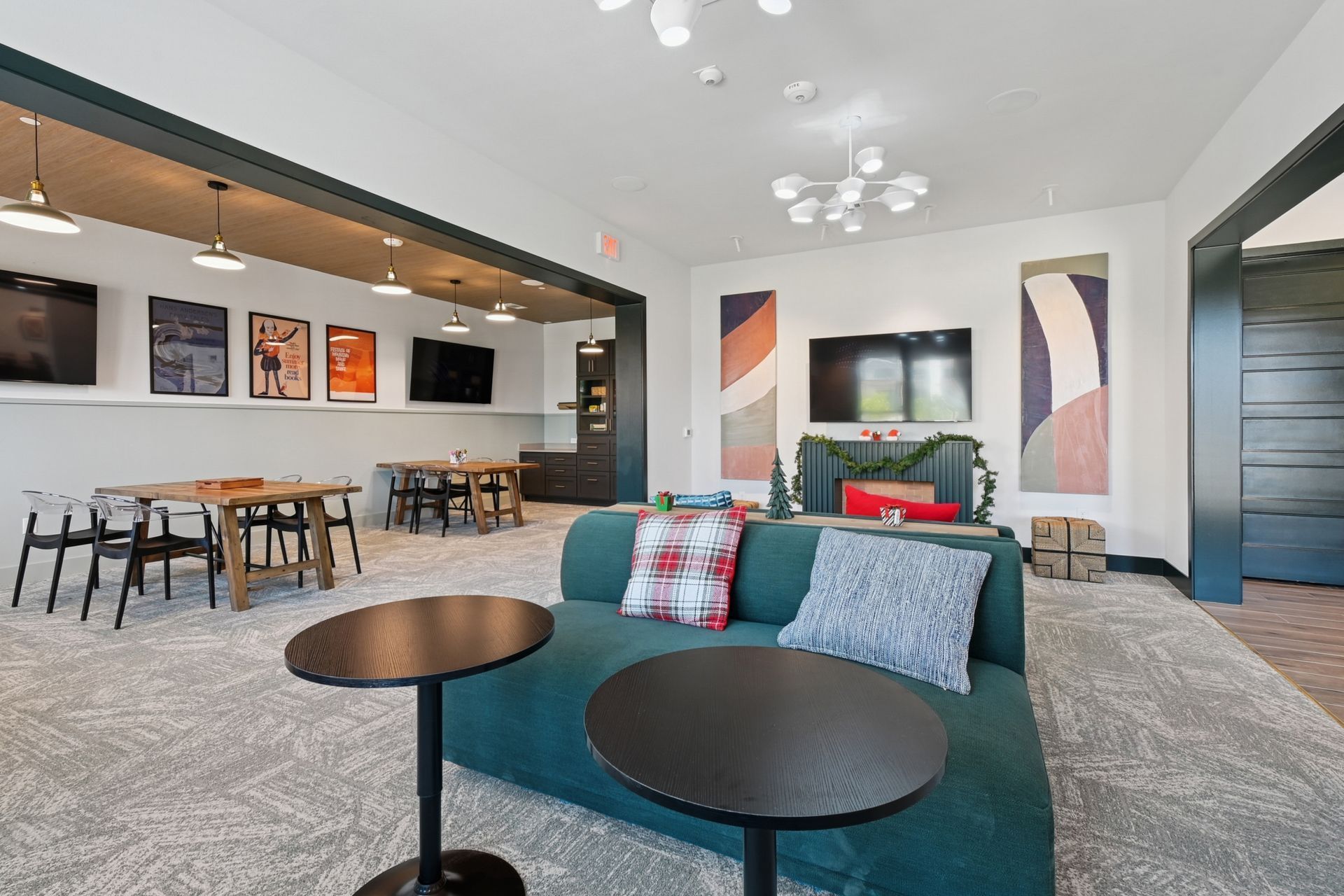 Modern open-plan living room with teal sofa, round tables, and dining area with bar stools
