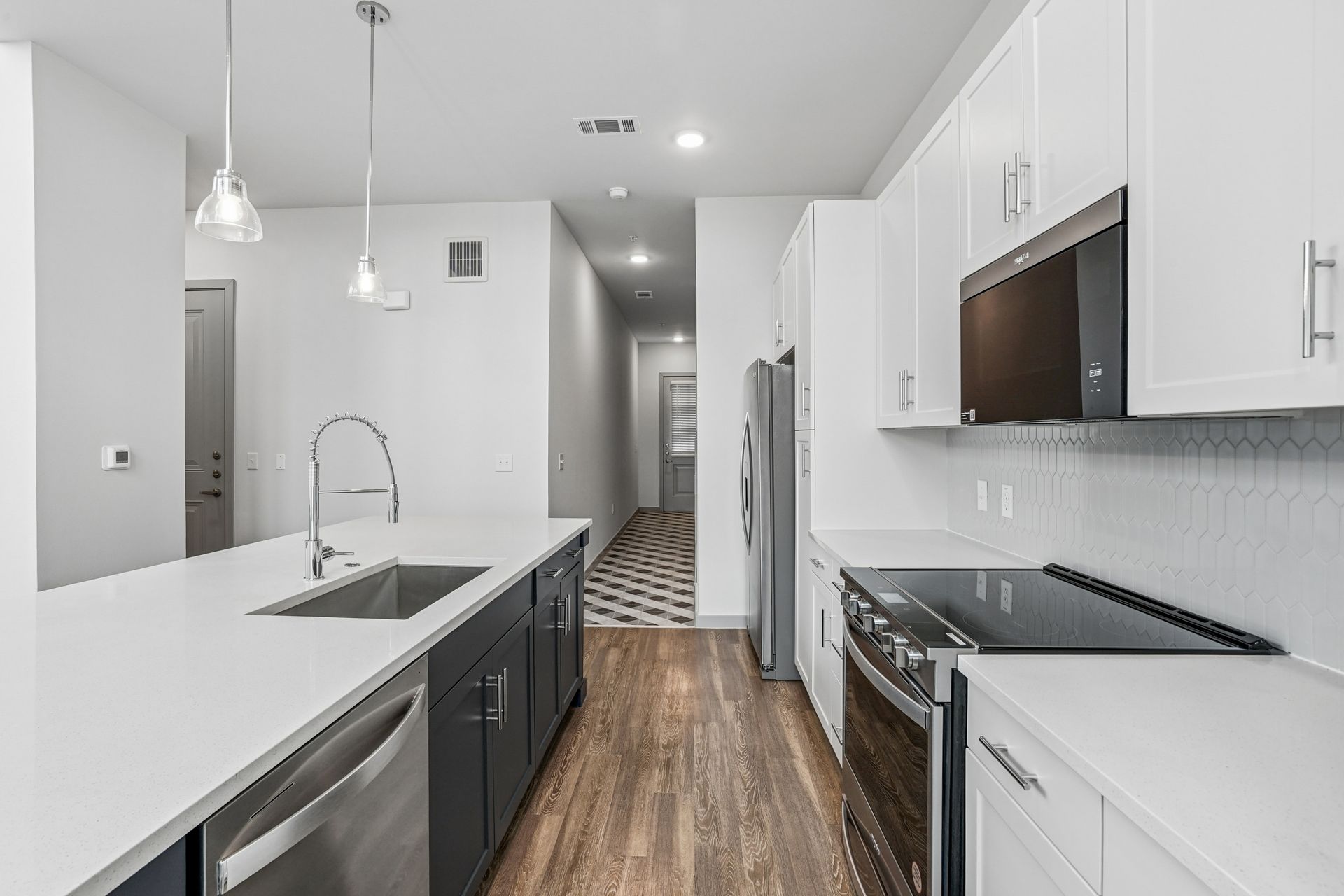 Modern kitchen with white cabinets, gray island, stainless appliances, and wood floors