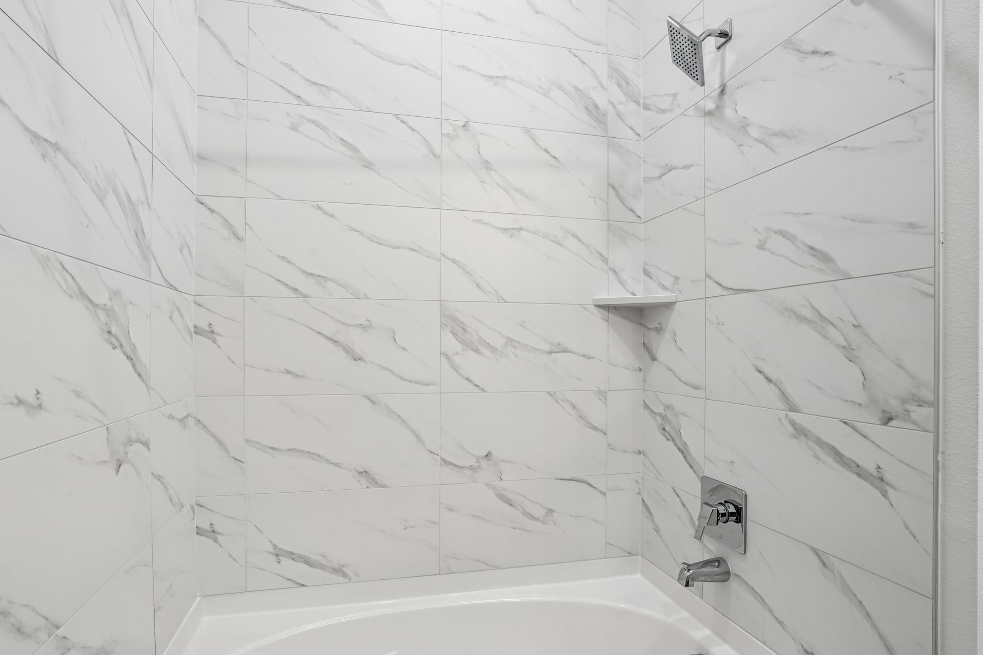 White marble-tile bathroom with a bathtub and shower fixtures