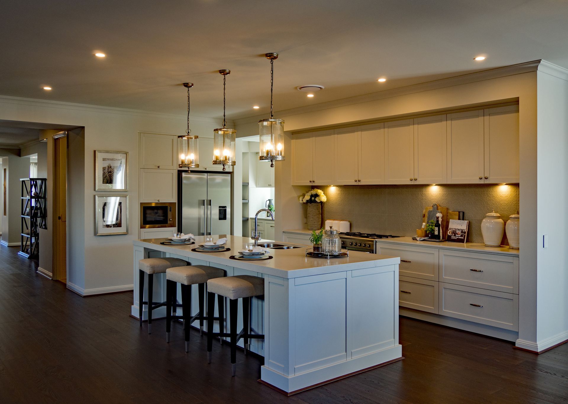 Modern kitchen with island, pendant lights, bar stools, and white cabinetry in an open floor plan Modern kitchen with island, pendant lights, bar stools, and white cabinetry in an open floor plan