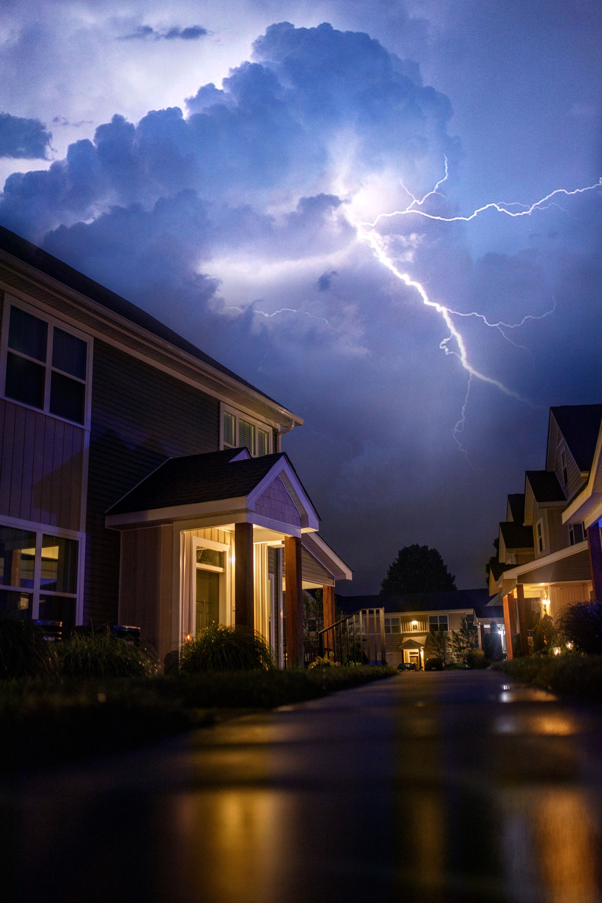 Small house beneath a storm cloud with lightning on a blue background