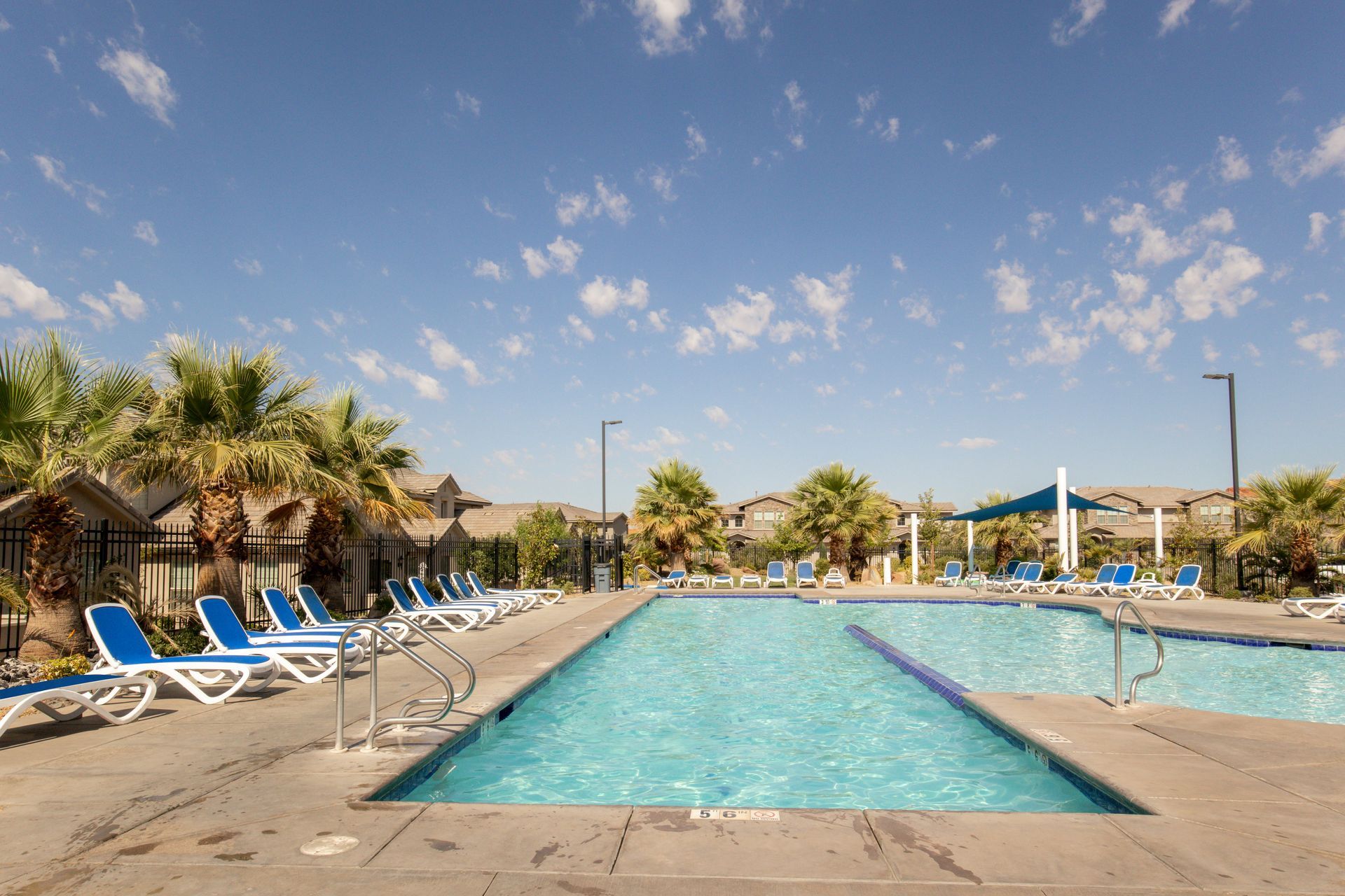 Casitas at Sienna Hills swimming pool surrounded by chairs and palm trees on a sunny day.