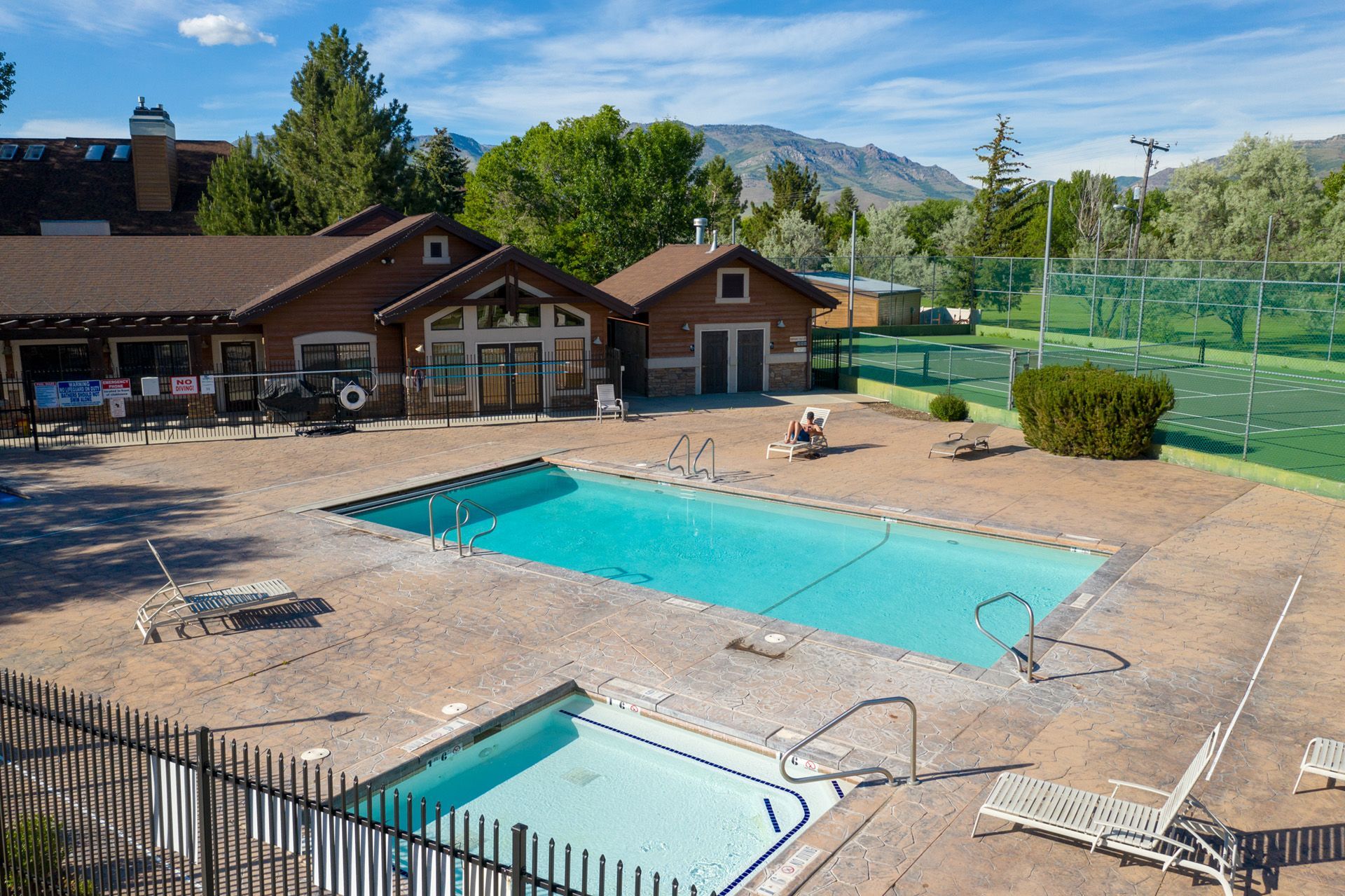 A large swimming pool surrounded by chairs and palm trees on a sunny day.
