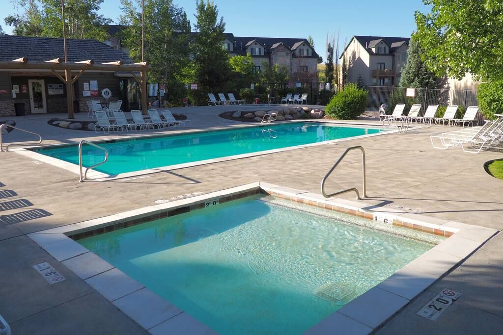 Moose Hollow Community swimming pool and hot tub, surrounded by lounge chairs and trees.