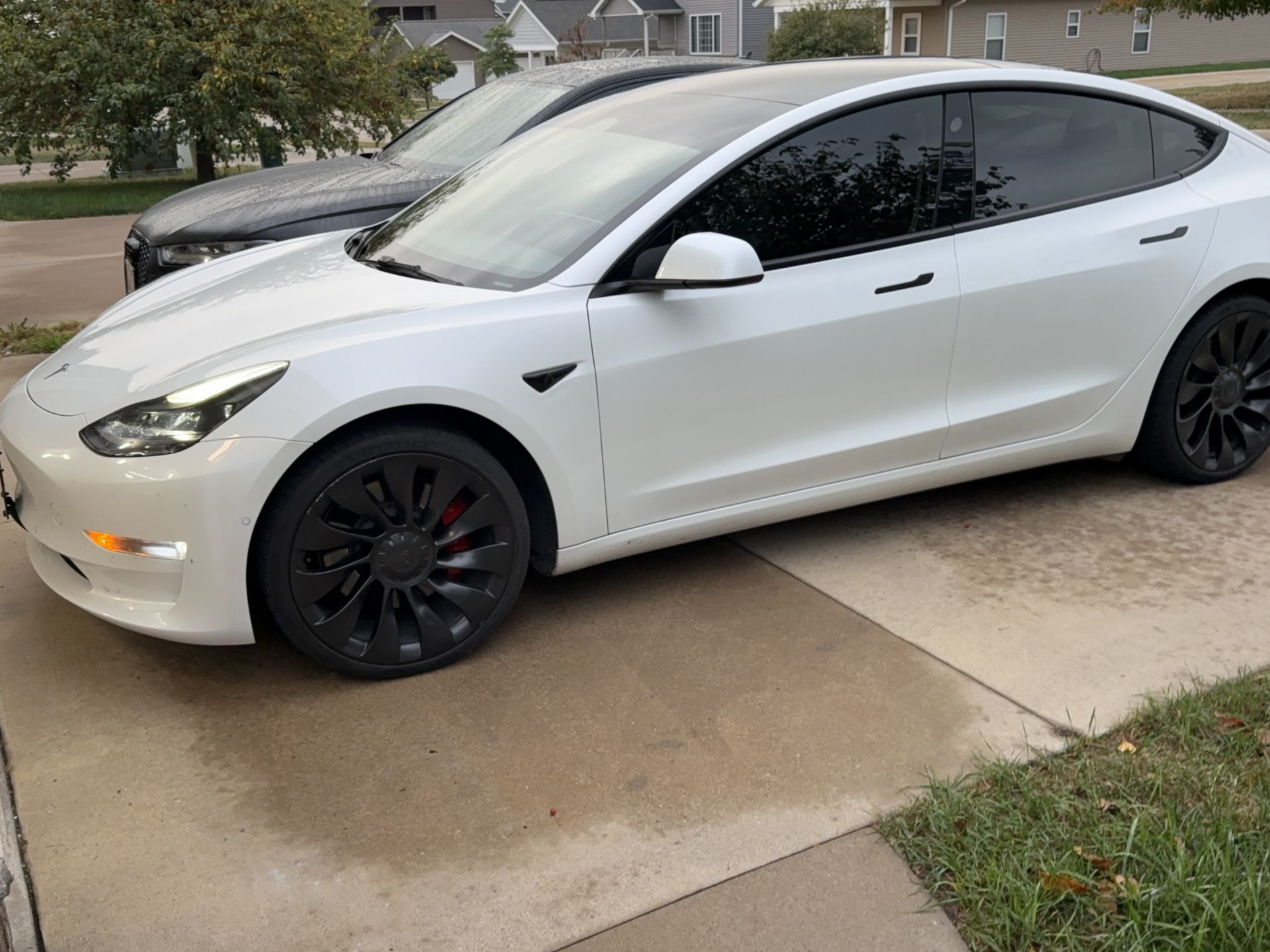 Silver luxury sedan with full window tint outside a residential garage