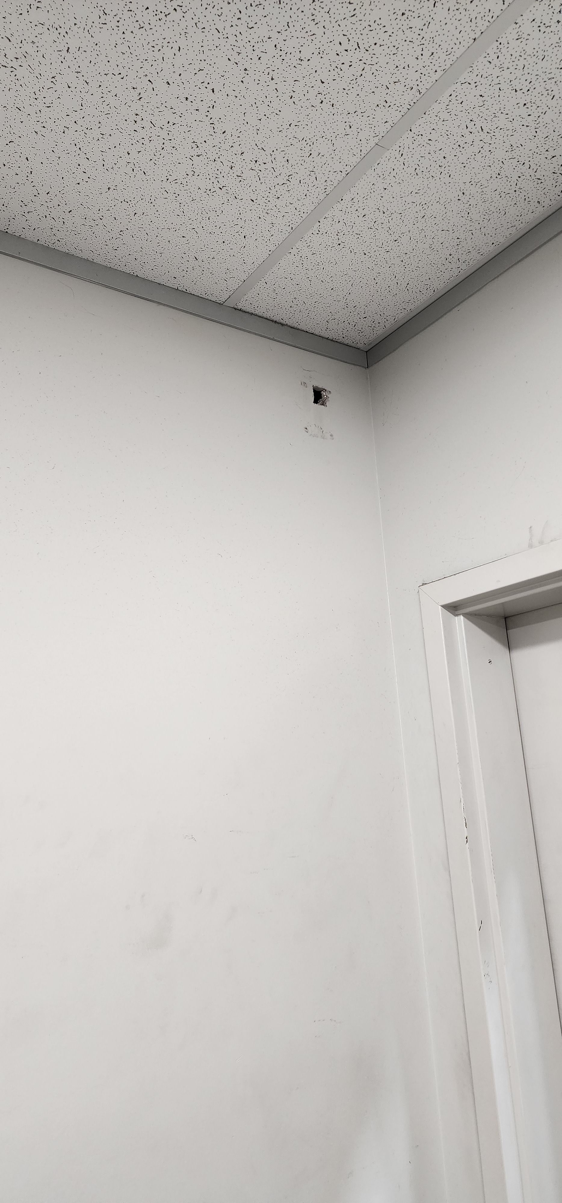 Corner of a room with a white wall, a textured ceiling, and a doorway.