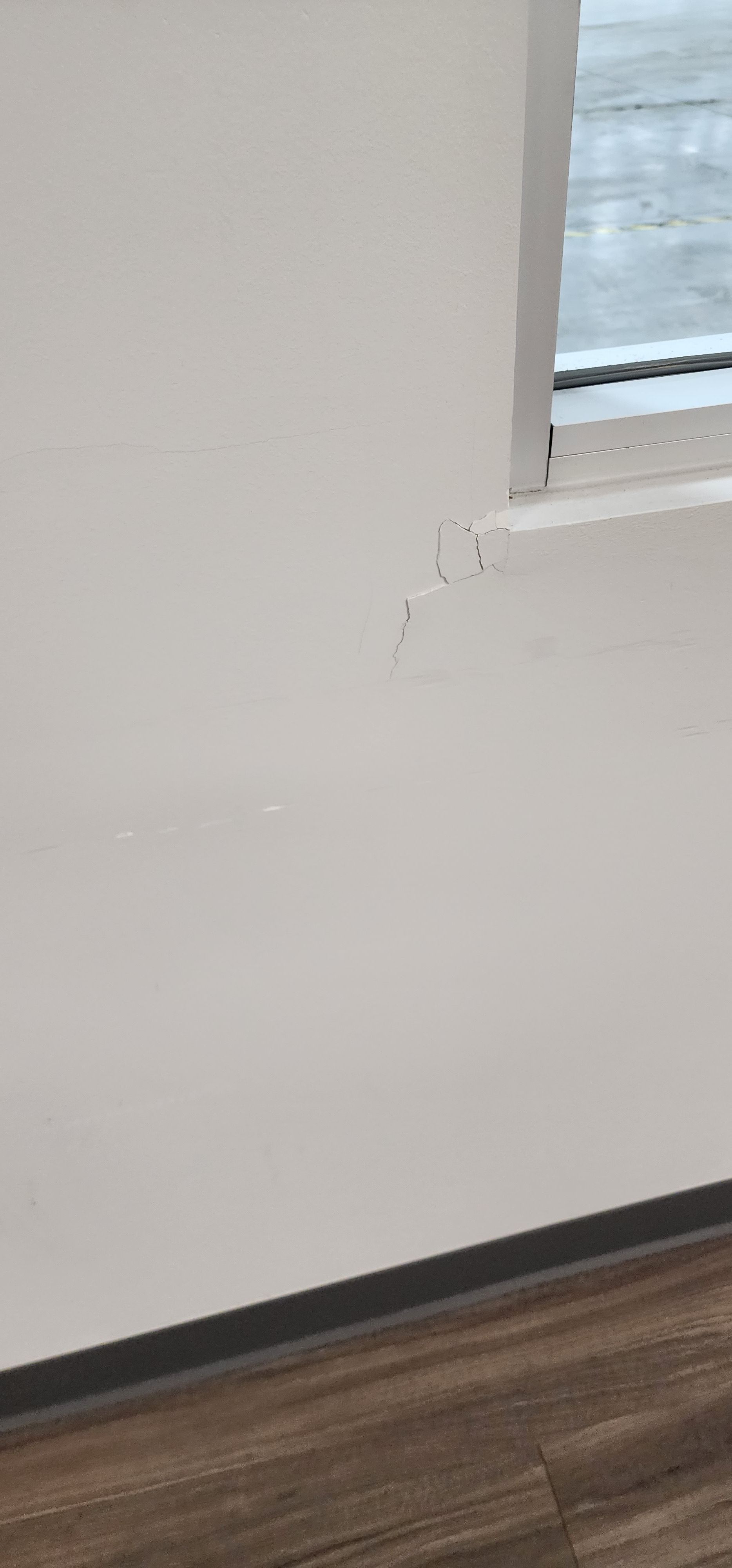 White wall with a dark border above a wood-look floor; a window is in the top right.