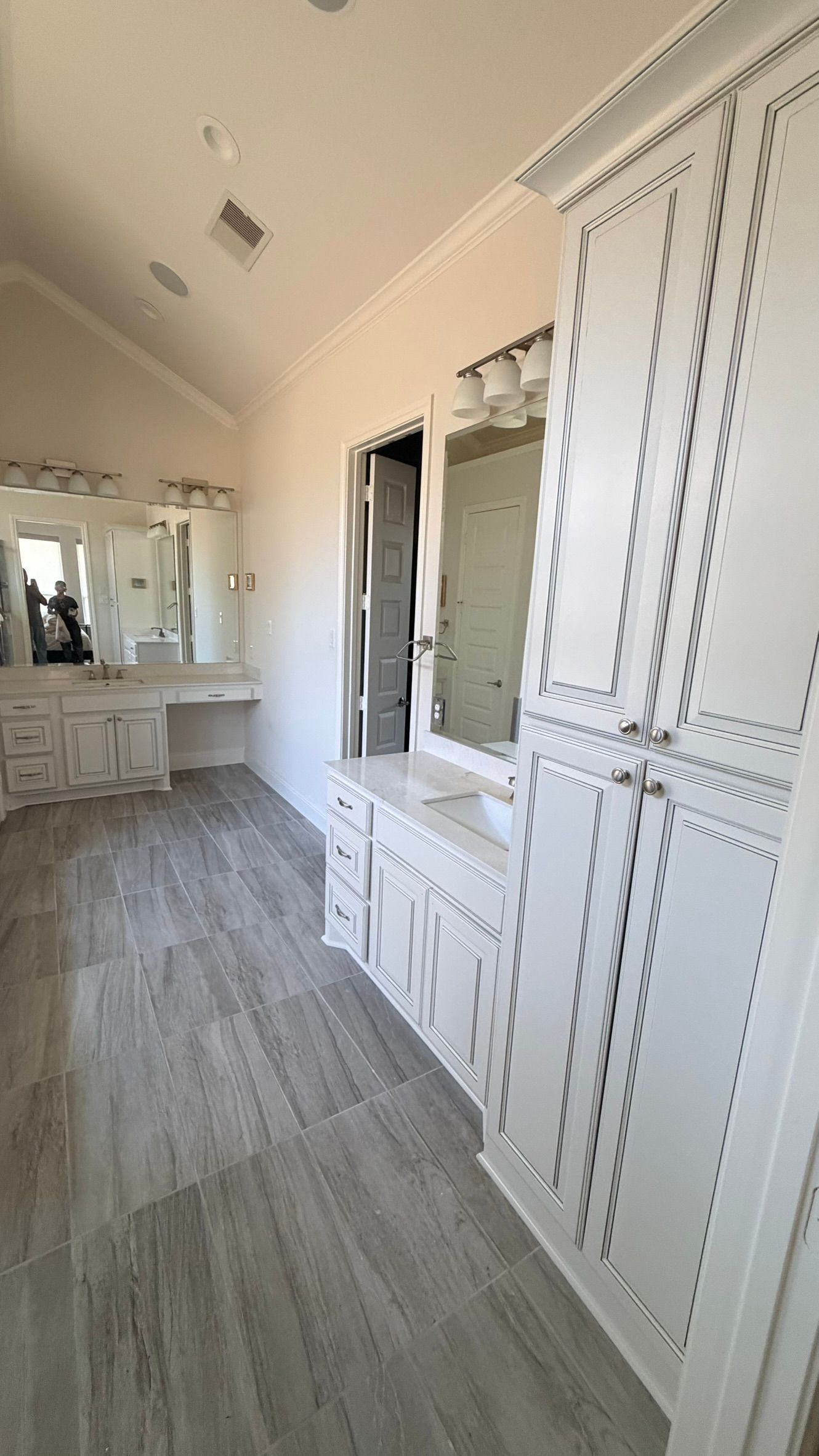 Bright white dressing room with built-in cabinets, vanity mirrors, and light wood flooring