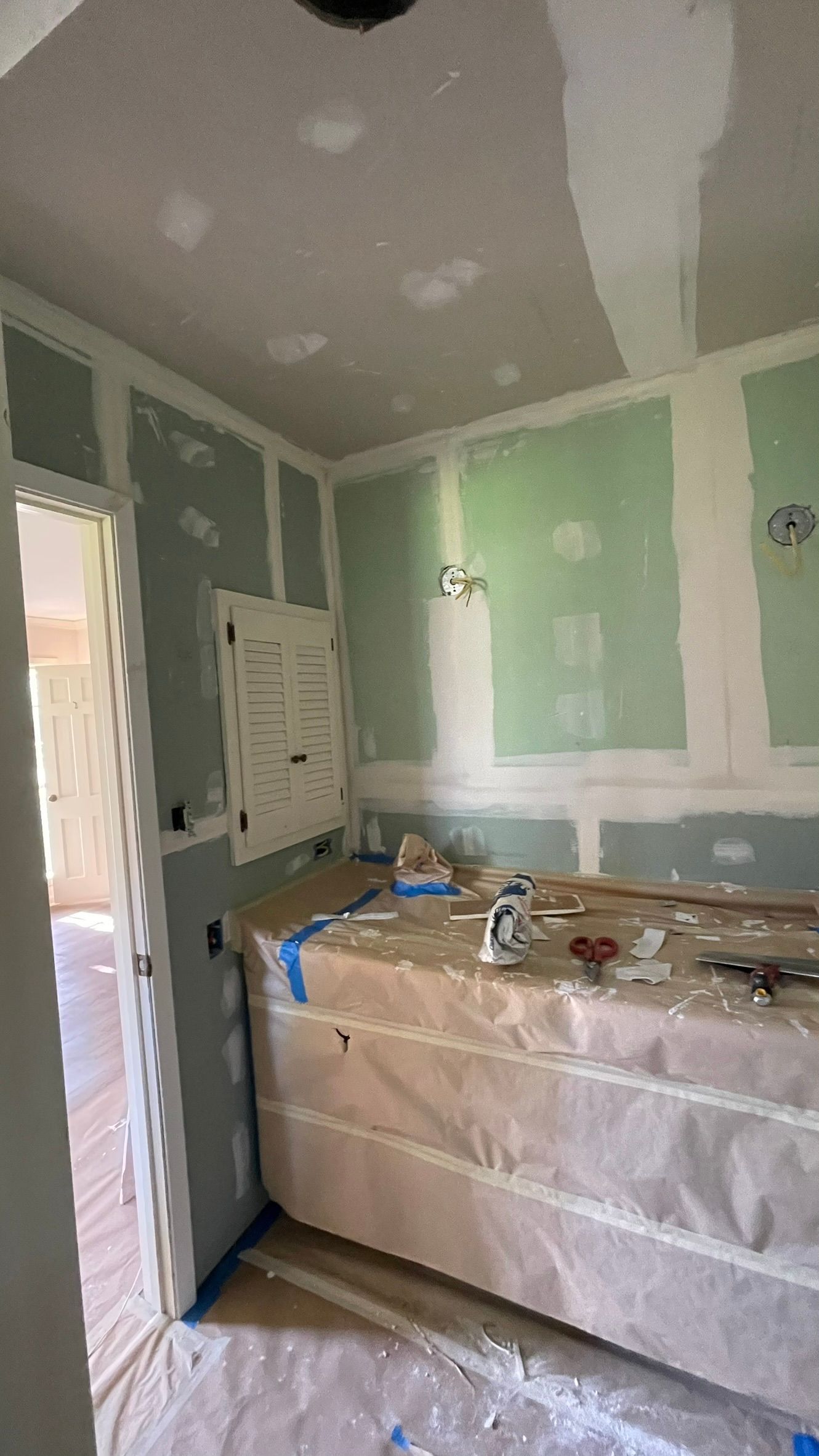Interior room under construction, green drywall, unfinished countertop, and open doorway.