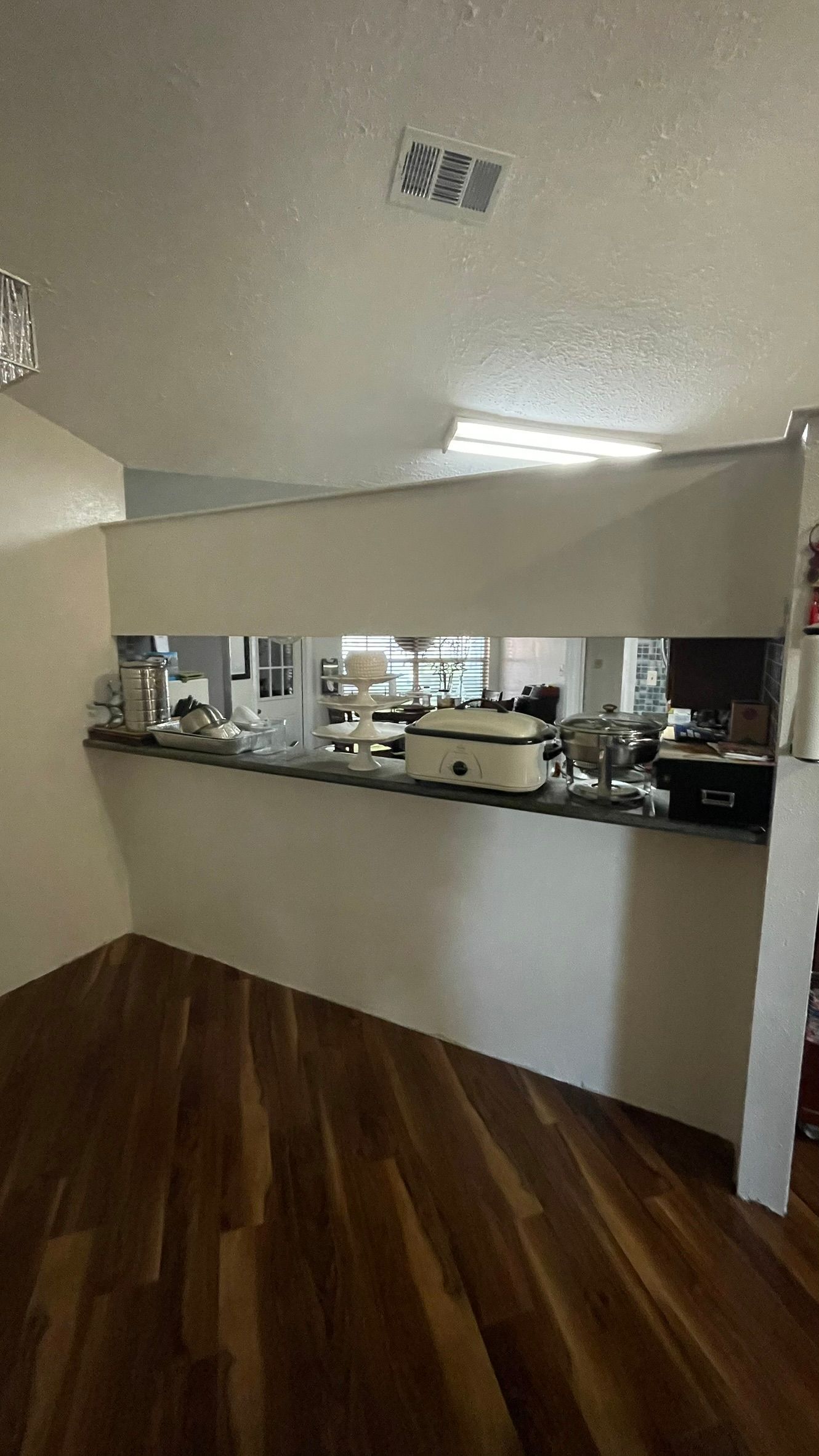 Kitchen passthrough with a counter, overhead lighting, and wooden flooring.