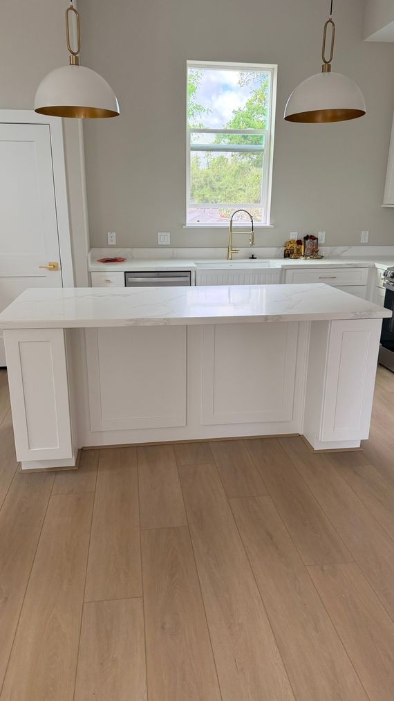 Modern kitchen with gray cabinets, white countertop, subway tile backsplash, and wood flooring.