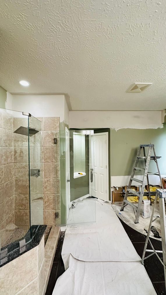 Luxury marble-tiled shower with gold fixtures, overhead rain shower, built-in shelf, and recessed lighting.