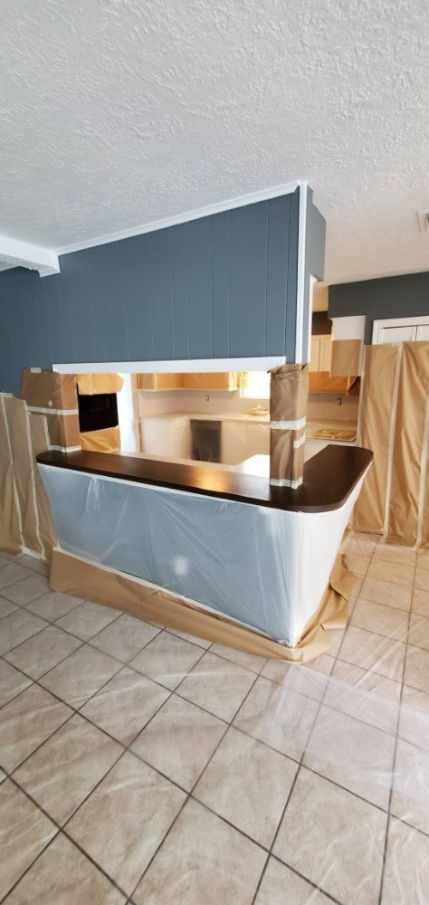 Bar area under construction with protective covering, gray walls, and tile flooring.