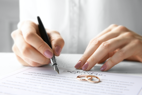 A woman is writing on a piece of paper with a fountain pen.