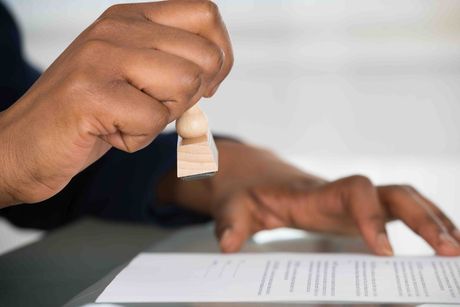 A person is stamping a piece of paper with a wooden stamp.