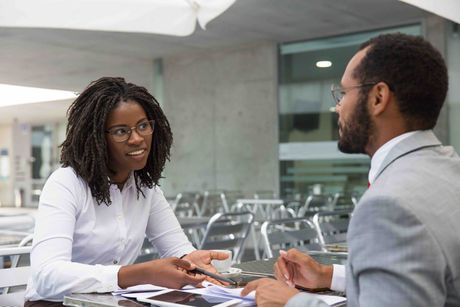 A man and a woman are sitting at a table having a conversation.