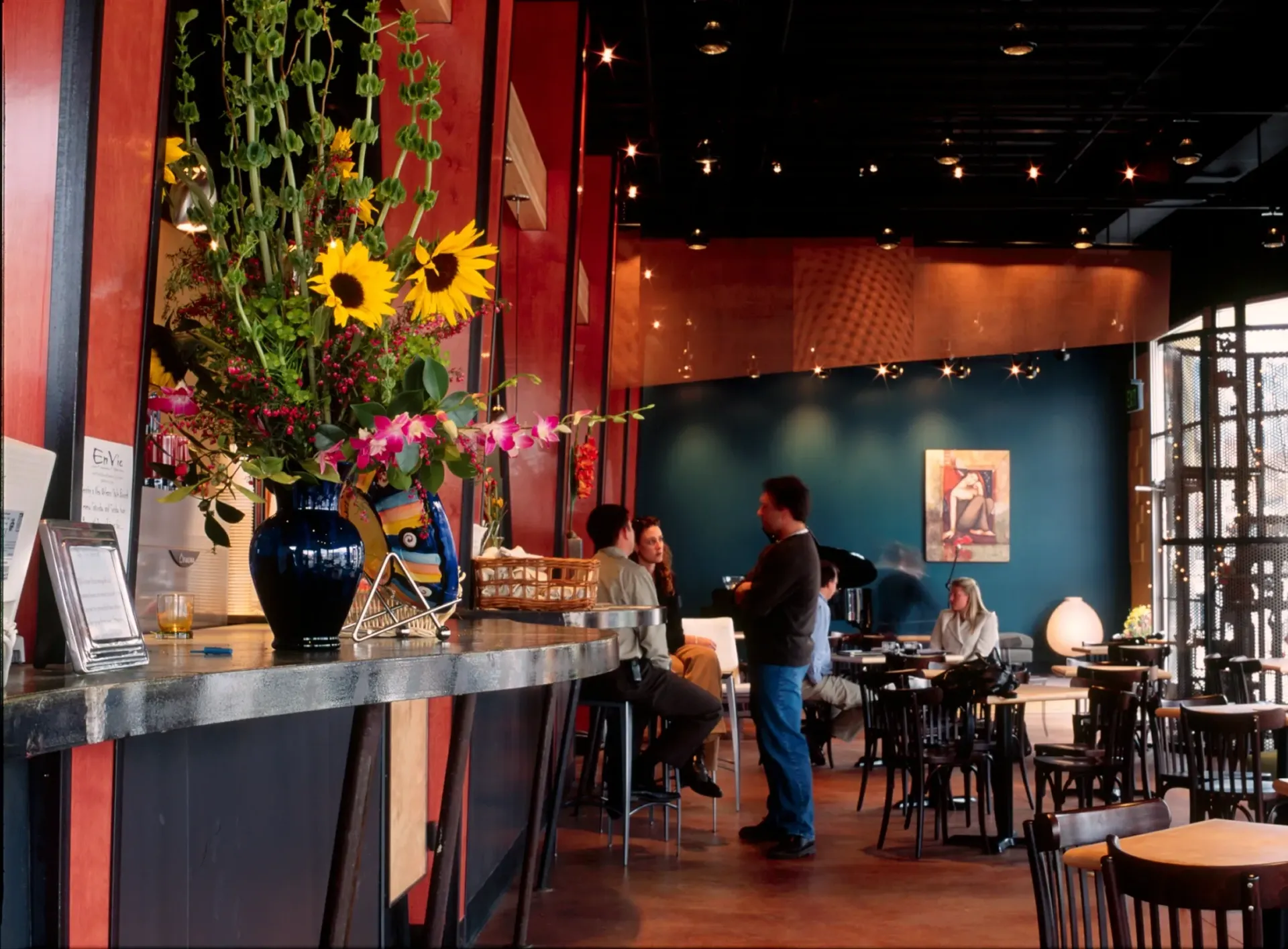 A restaurant with people sitting at tables and a man standing at the bar
