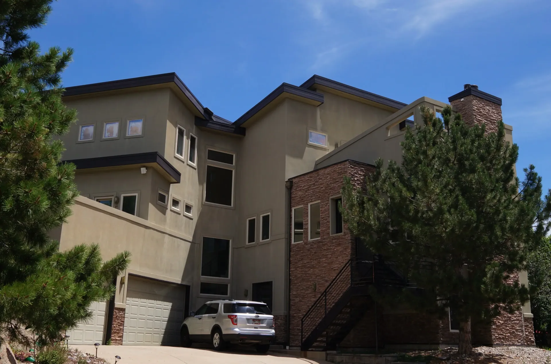 A white suv is parked in front of a large house