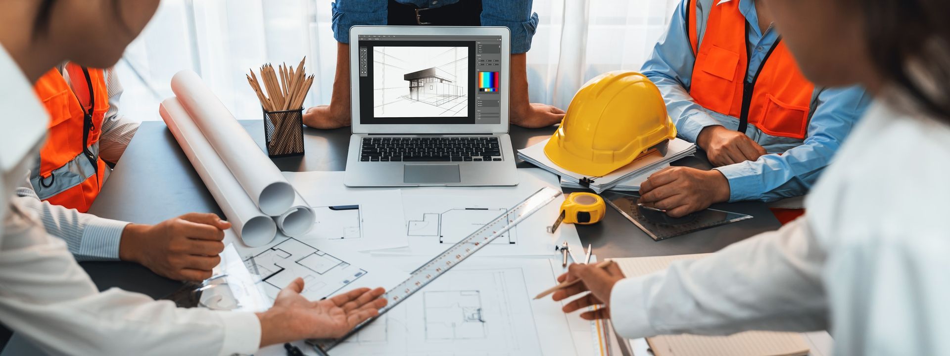 A group of construction workers are sitting around a table looking at blueprints.