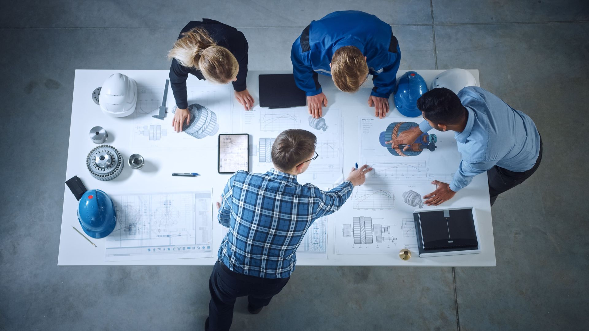 A group of people are sitting around a table looking at blueprints.