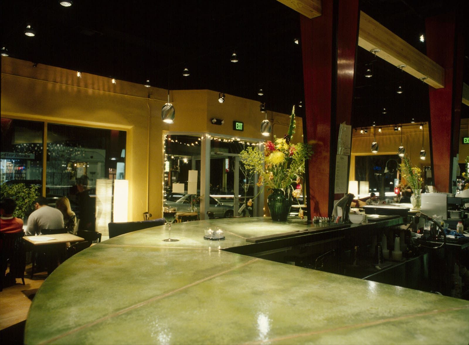 A restaurant with a green exit sign on the ceiling