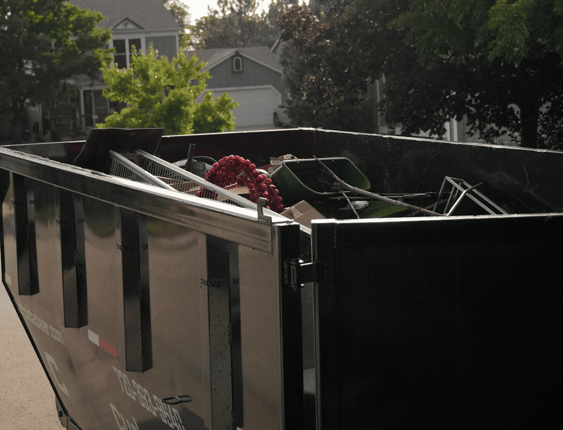 Curbside Clear roll-off dumpster filled with household debris from a home cleanup project.