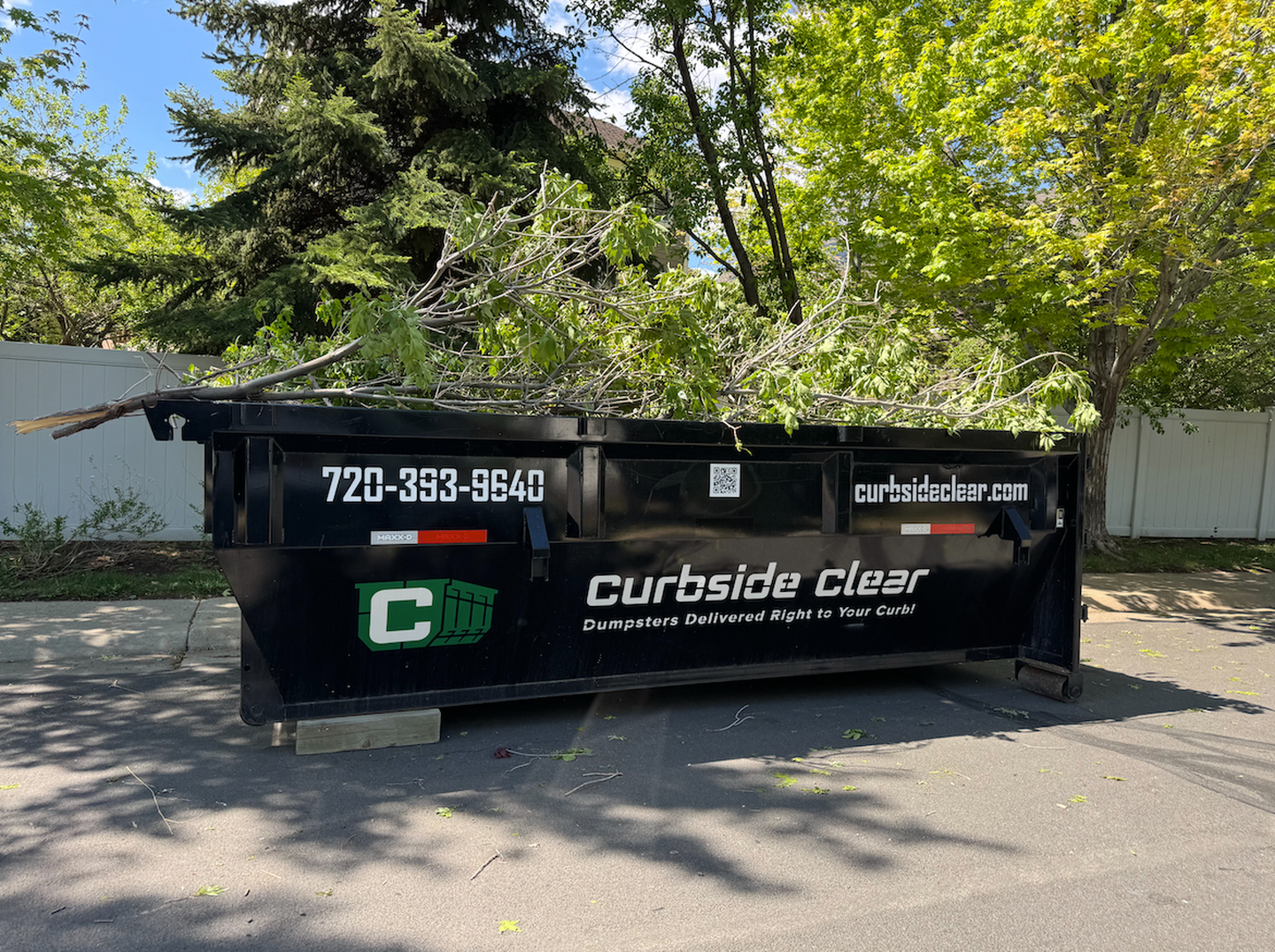 Curbside Clear dumpster loaded with yard waste for Lakewood CO landscaping project
