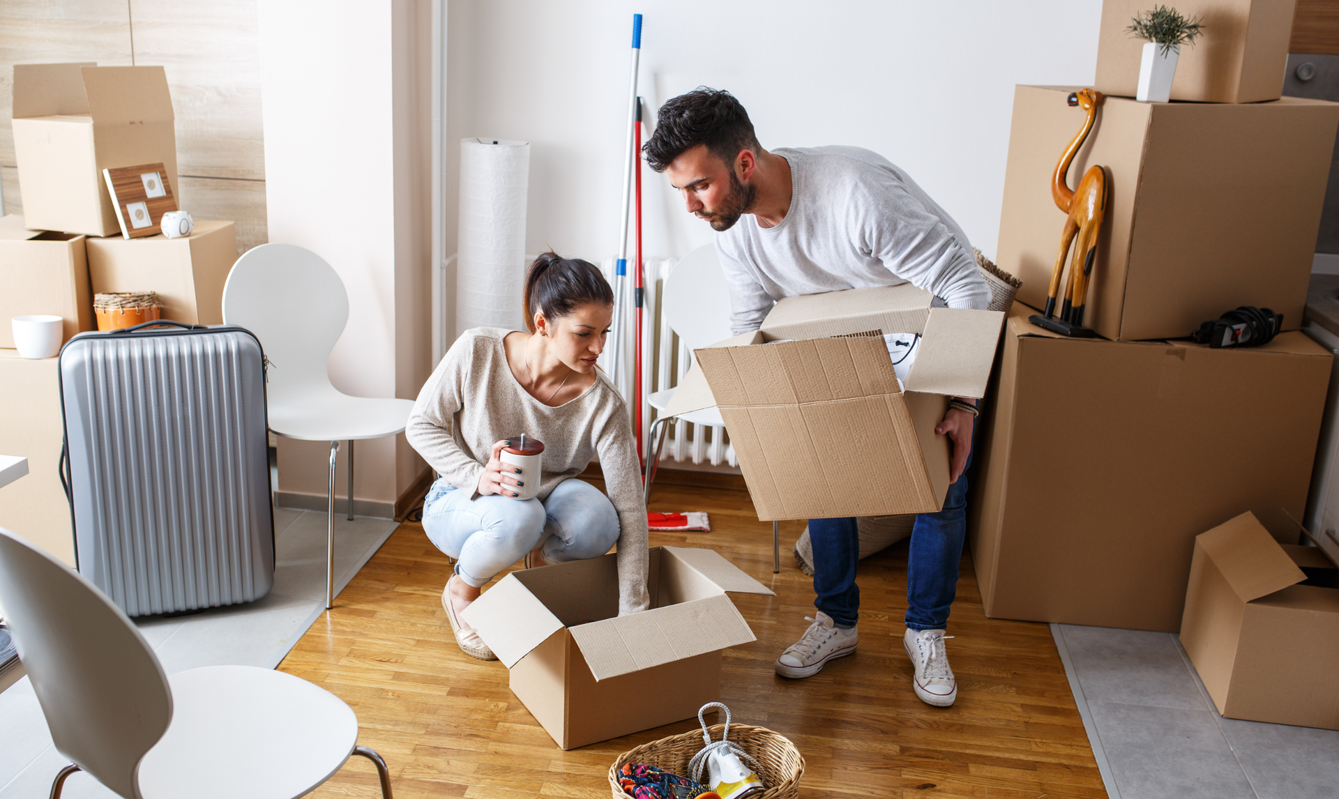 A couple unpacking cardboard boxes in their new home, surrounded by moving supplies and packed containers. A couple unpacking cardboard boxes in their new home, surrounded by moving supplies and packed containers.