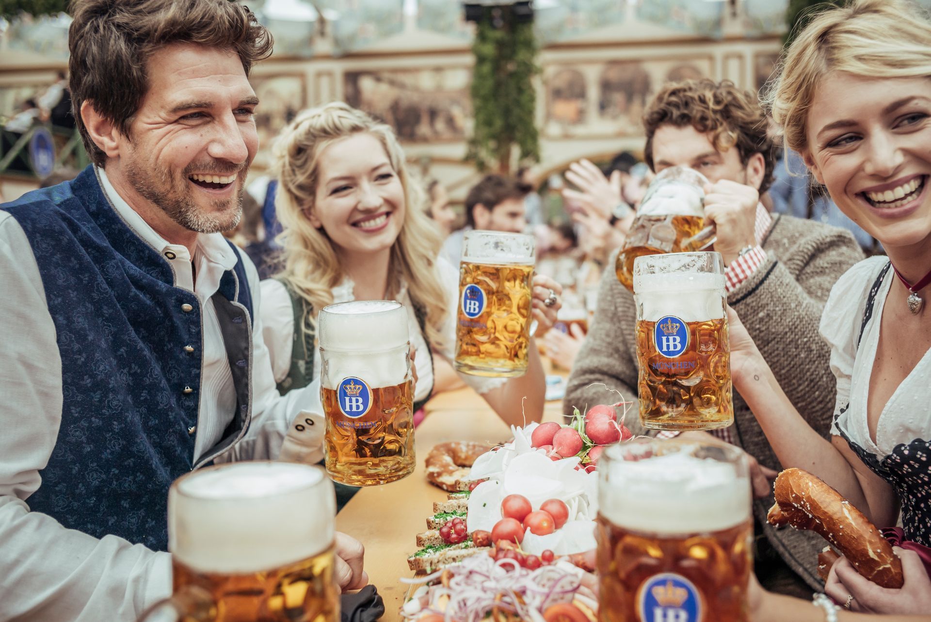 People clinking beer glasses in a warm, festive bar setting