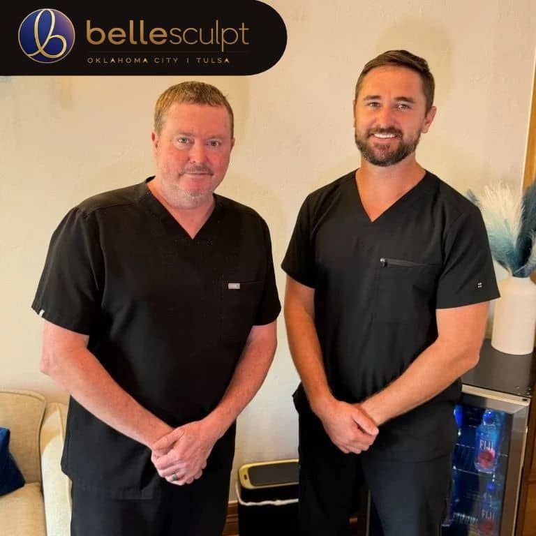 BelleSculpt Oklahoma Surgeons - Owners Two Doctors in black scrubs standing in a BelleSculpt clinic reception area
