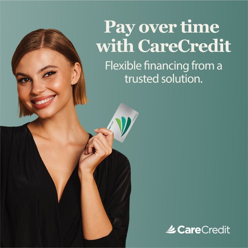 Smiling woman holding CareCredit card with text, “Pay over time with CareCredit” on teal background