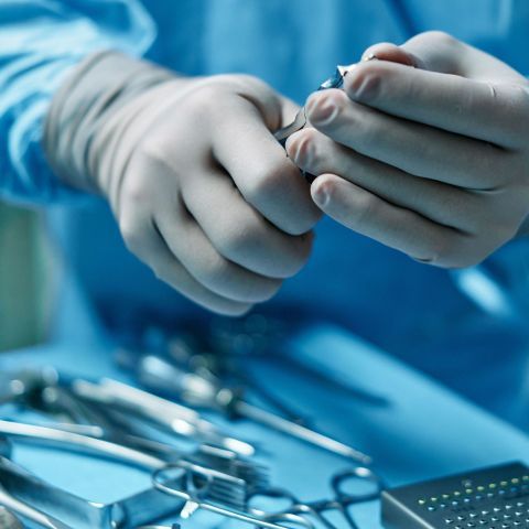 Gloved clinician using device device on patient’s abdomen in a medical exam room