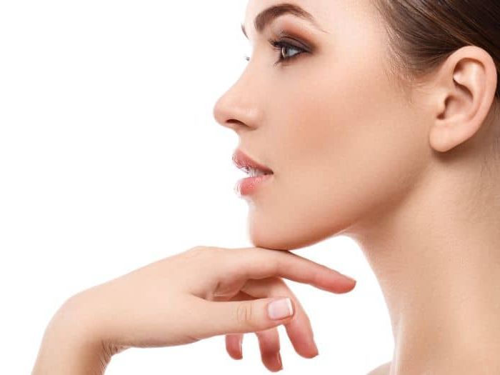 Close-up profile of a woman resting her chin on her hand against a white background