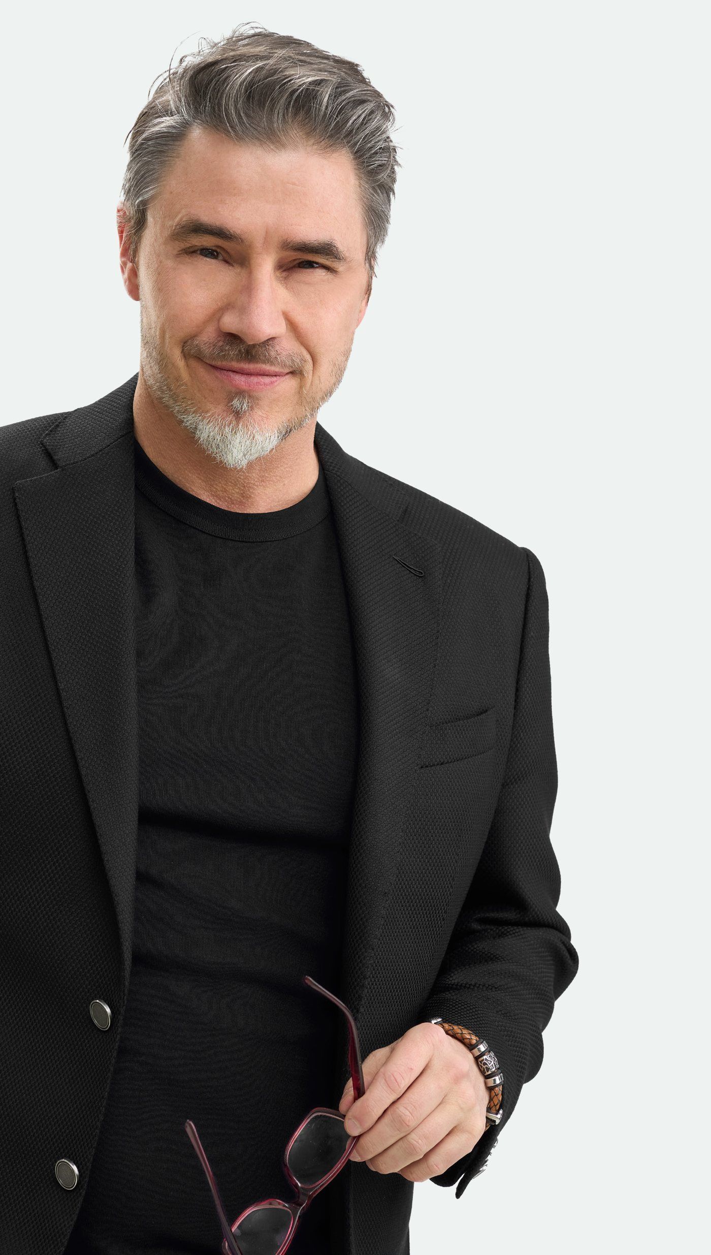 Confident man in his forties with salt and pepper hair wearing a black blazer