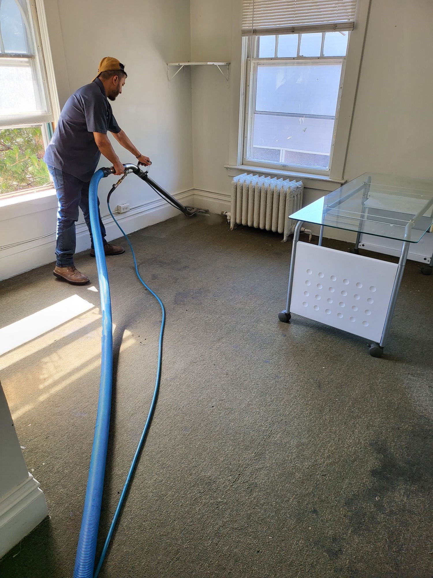 A man is using a vacuum cleaner to clean a carpet in a room.
