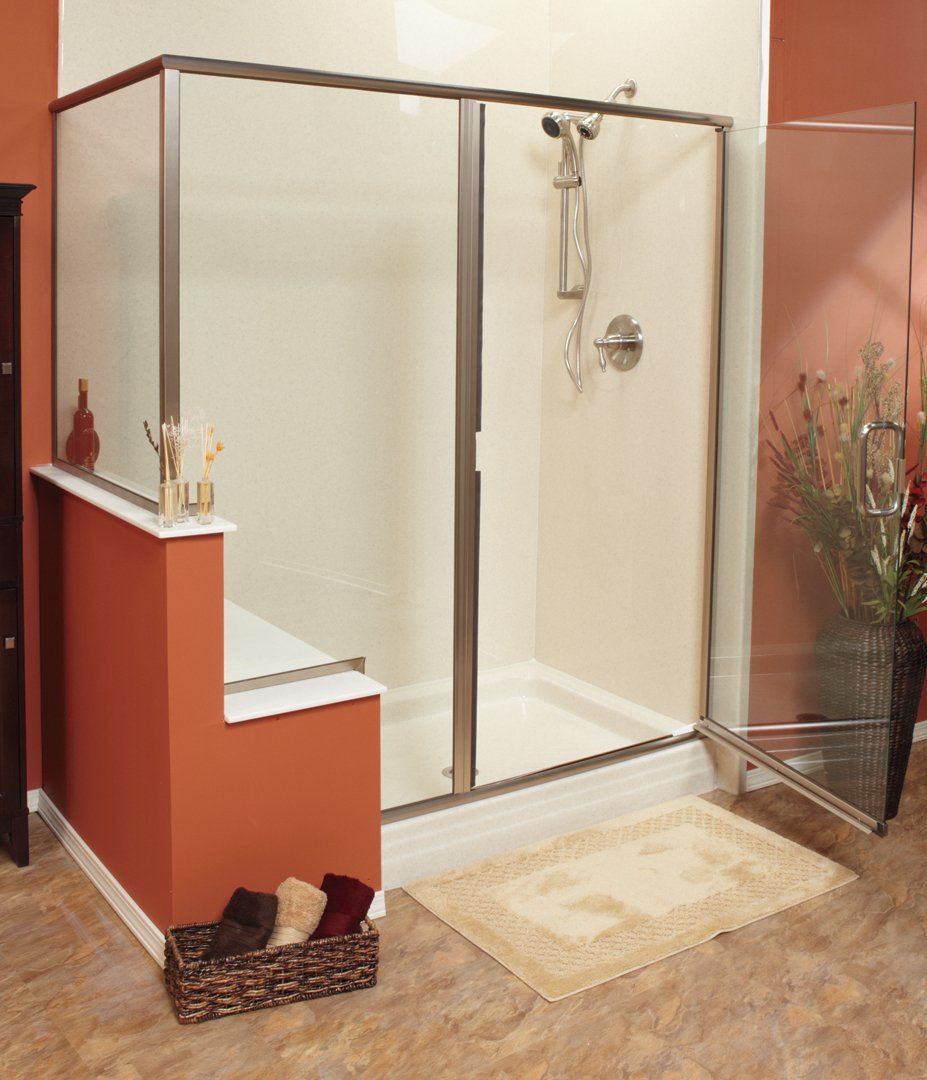 A walk-in shower with a glass enclosure, a low half-wall, and a built-in bench in a bathroom with terracotta-colored walls.