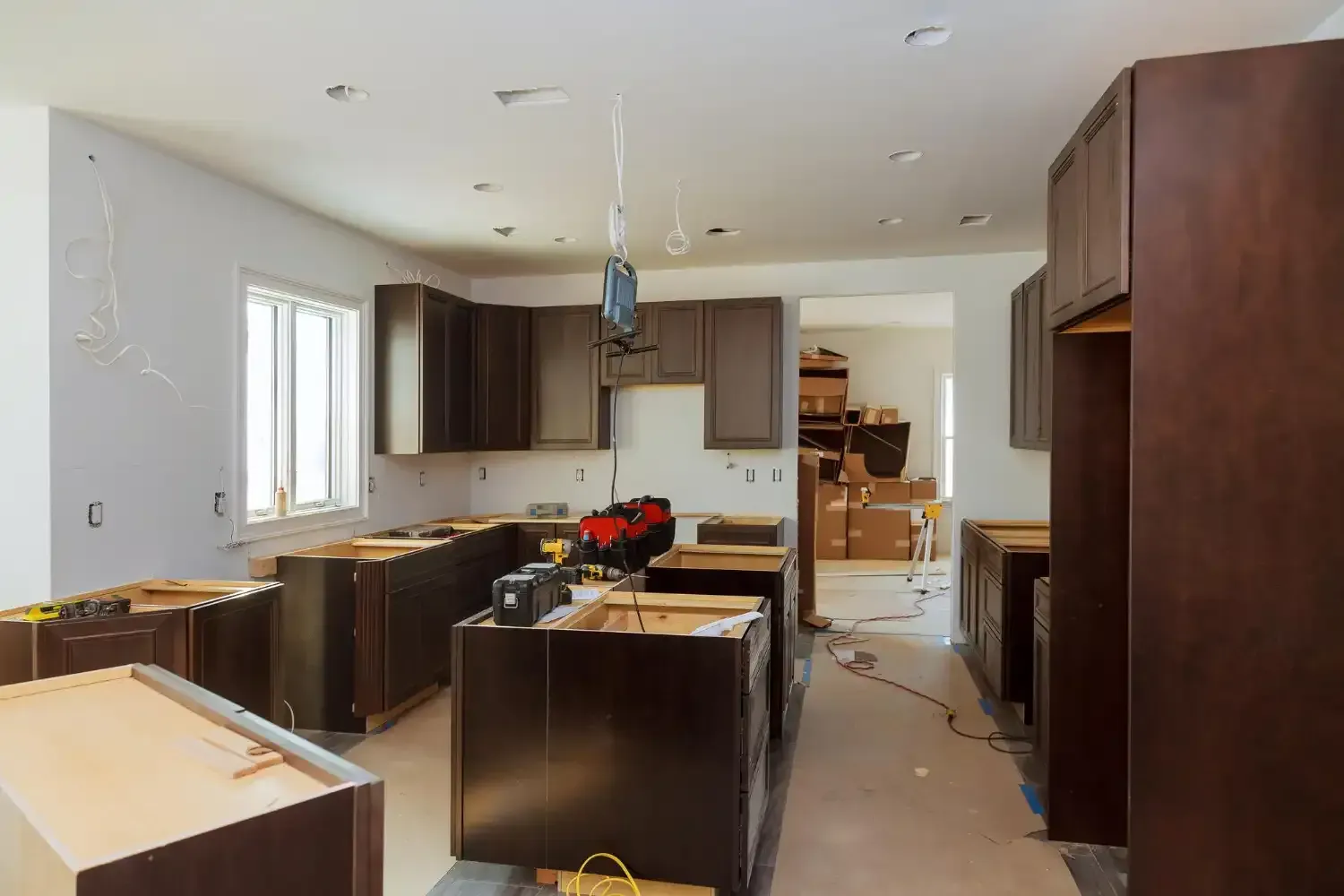 Kitchen under renovation with dark wood cabinets, unfinished countertops, and tools on the floor