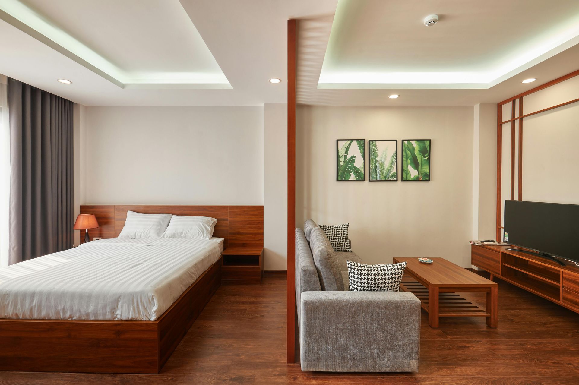 Condo room with a bed, sofa, TV, wooden accents, and artwork.