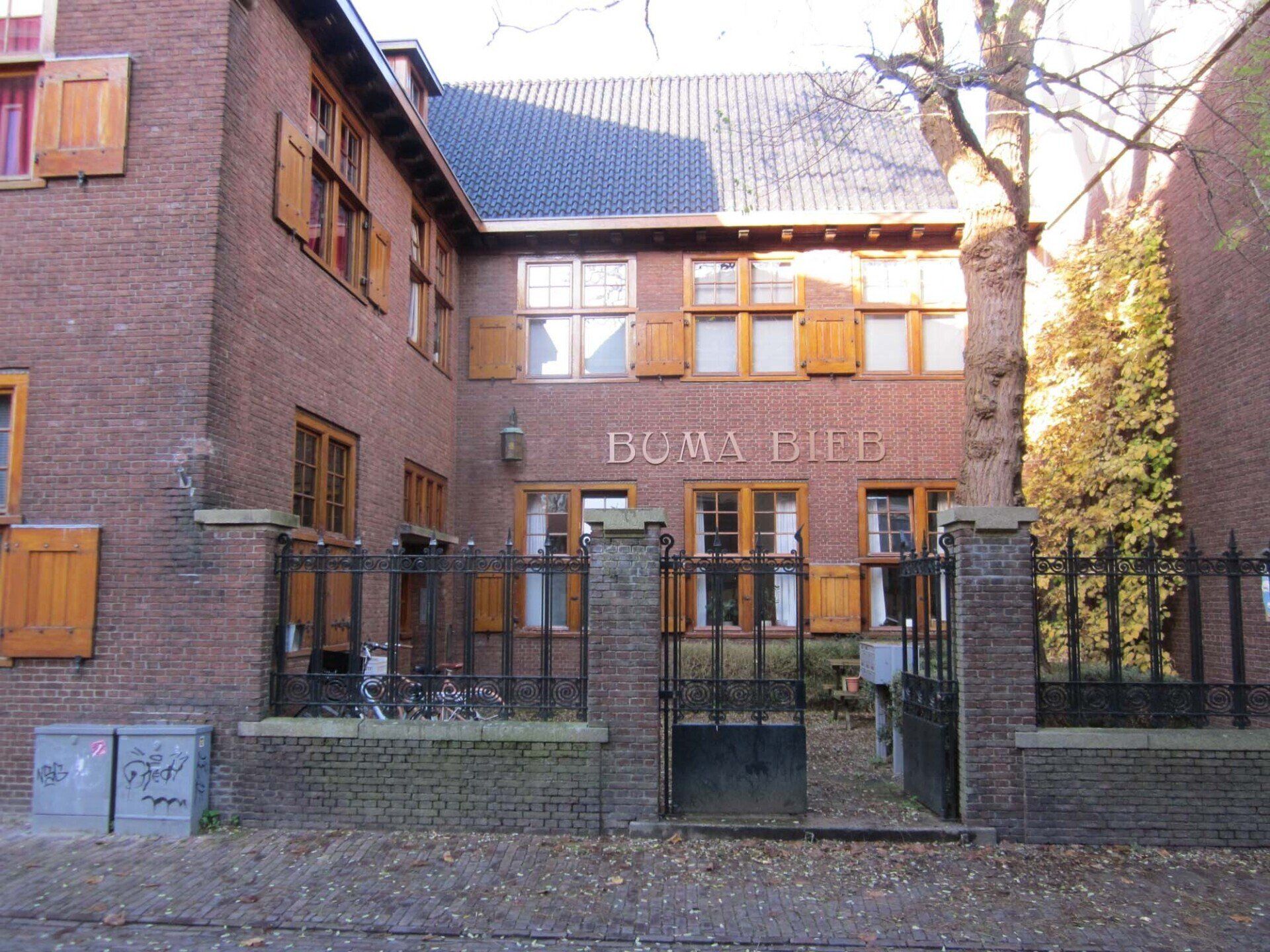 Een bakstenen gebouw met een afgesloten ingang en ramen, gezien vanaf een binnenplaats bij daglicht.
