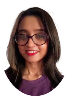 Woman with dark hair and glasses smiles, wearing a purple shirt, red lipstick.