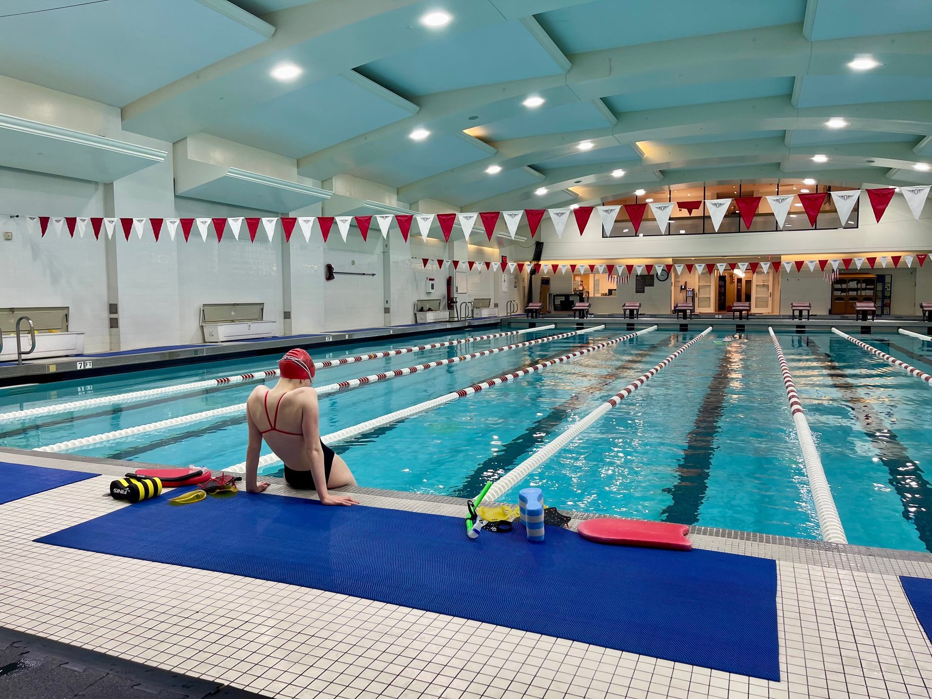 a woman sits on the edge of a large swimming pool