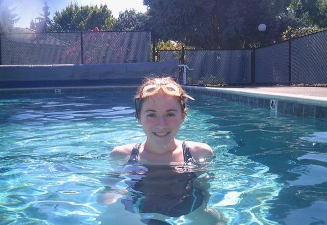 A woman wearing goggles is swimming in a pool.
