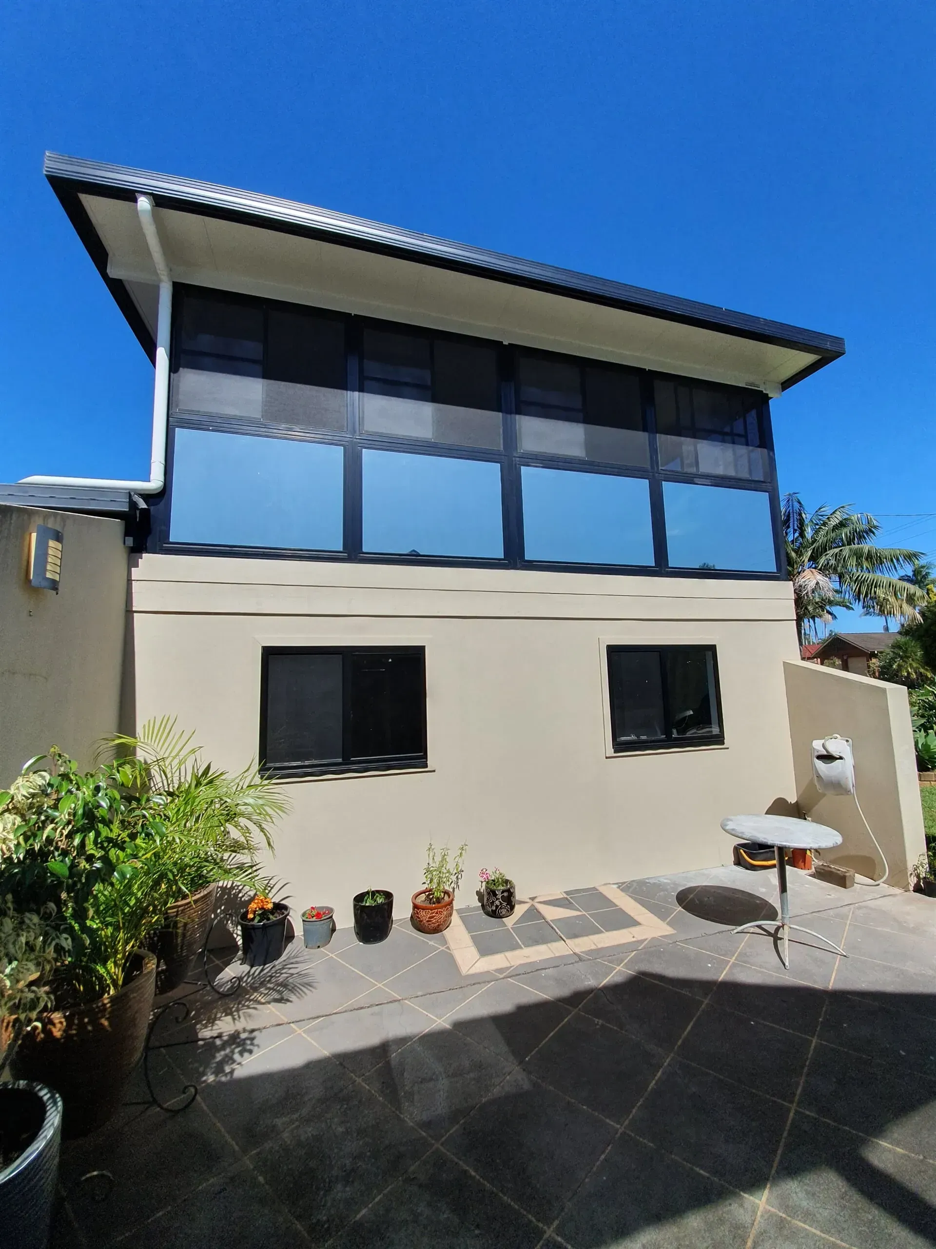 Modern two-story house exterior with large windows, beige walls, and a sunny blue sky — Awesome Window Tint In Kempsey, NSW