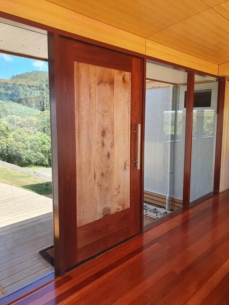 Open wooden sliding door leading to a deck, with hills and greenery outside — Awesome Window Tint In Kempsey, NSW