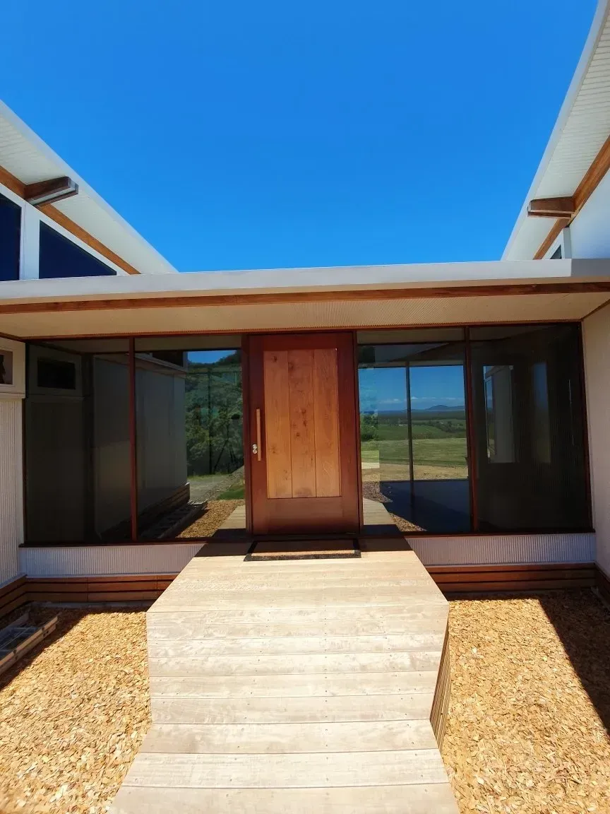 Modern house entry with a wooden front door, concrete walkway — Awesome Window Tint In Kempsey, NSW