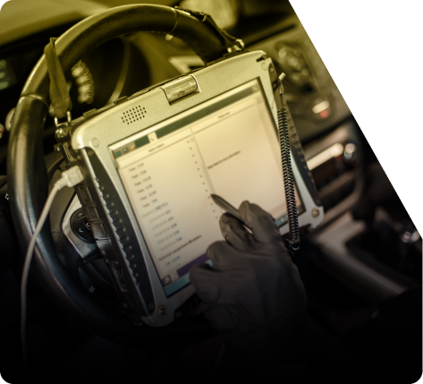 Person using a rugged tablet in a vehicle, with headset and gloved hand on the screen. | The Recon Garage