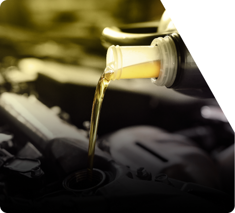 Oil being poured from a bottle into a car engine, close-up, with a yellow tint. | The Recon Garage