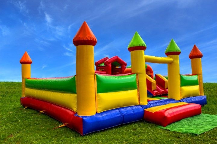 Colorful inflatable bounce house on a grassy field under a blue sky