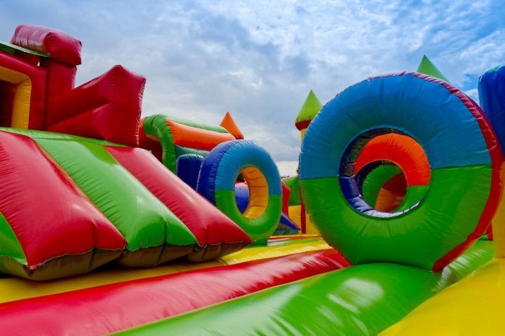 Colorful inflatable obstacle course with red, green, and blue tunnels under a cloudy sky