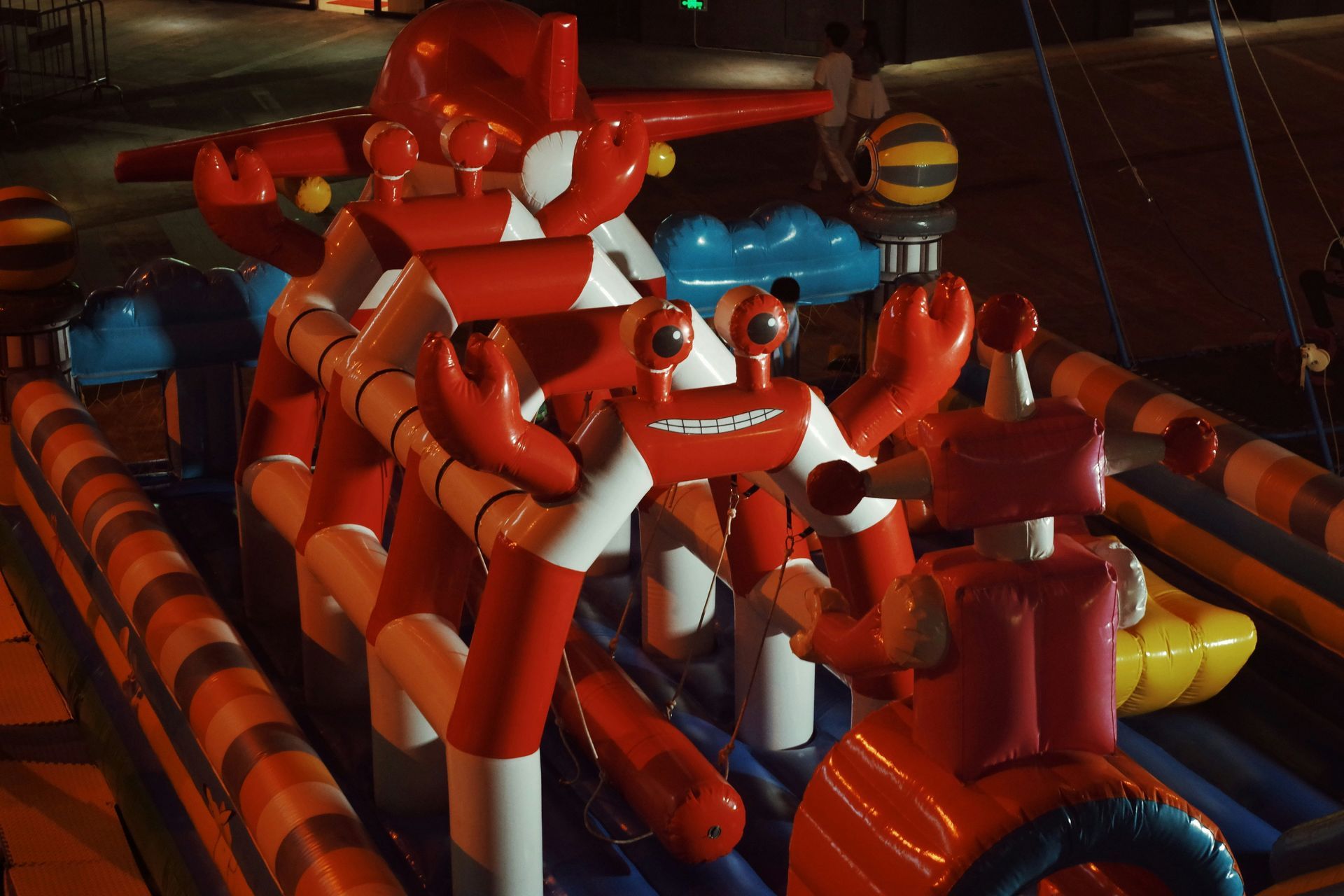 Inflatable red and orange obstacle course with tube tunnels and figures at night